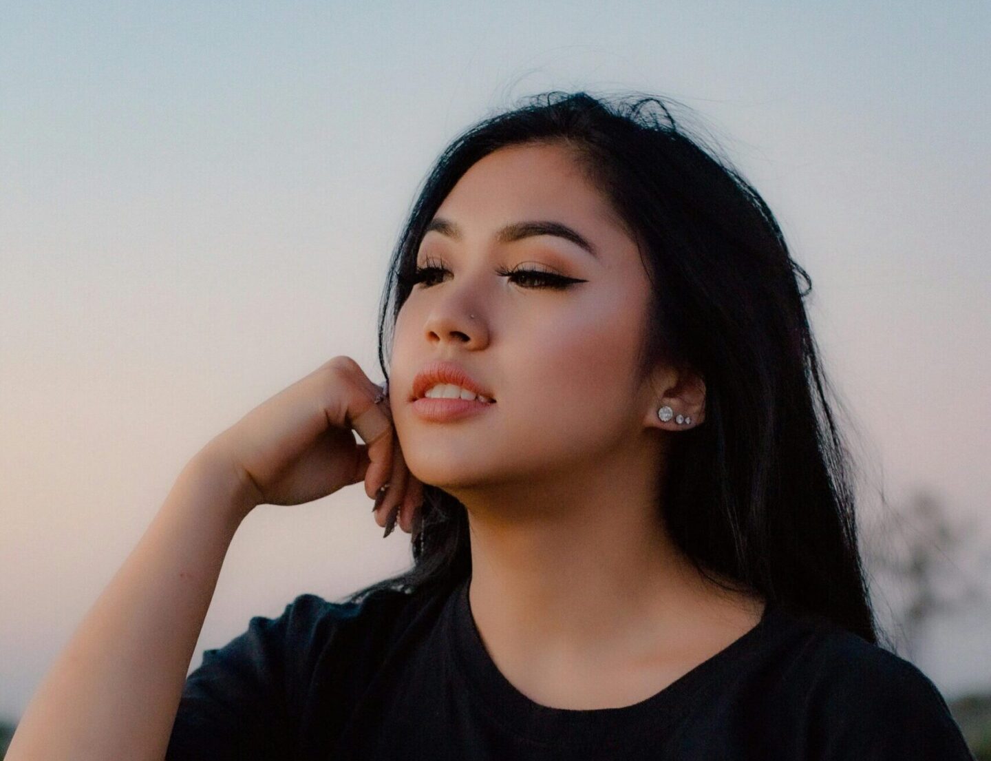 Teen sitting alone in nature at sunset, reflecting and finding peace during emotional recovery from trauma.