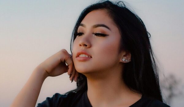 Teen sitting alone in nature at sunset, reflecting and finding peace during emotional recovery from trauma.