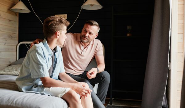 A parent and teen having a serious conversation about social media use, highlighting the importance of open communication to protect youth mental health.