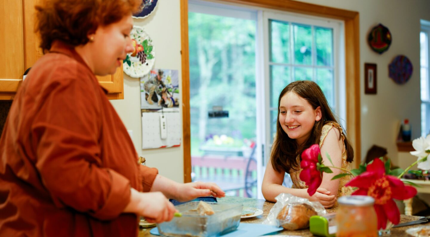 A parent and young child sitting in the kitchen together, smiling and talking during a daily emotional check-in