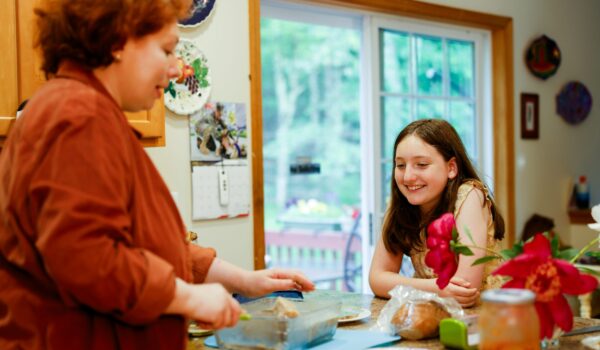 A parent and young child sitting in the kitchen together, smiling and talking during a daily emotional check-in