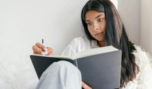 A teenager sitting and writing in a journal, reflecting on their thoughts and emotions.