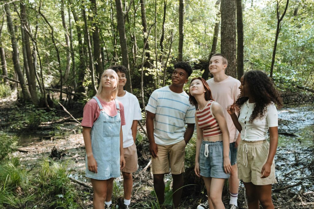 A diverse group of teenagers laughing together outdoors in the summer, representing genuine connection and enjoying the present moment.