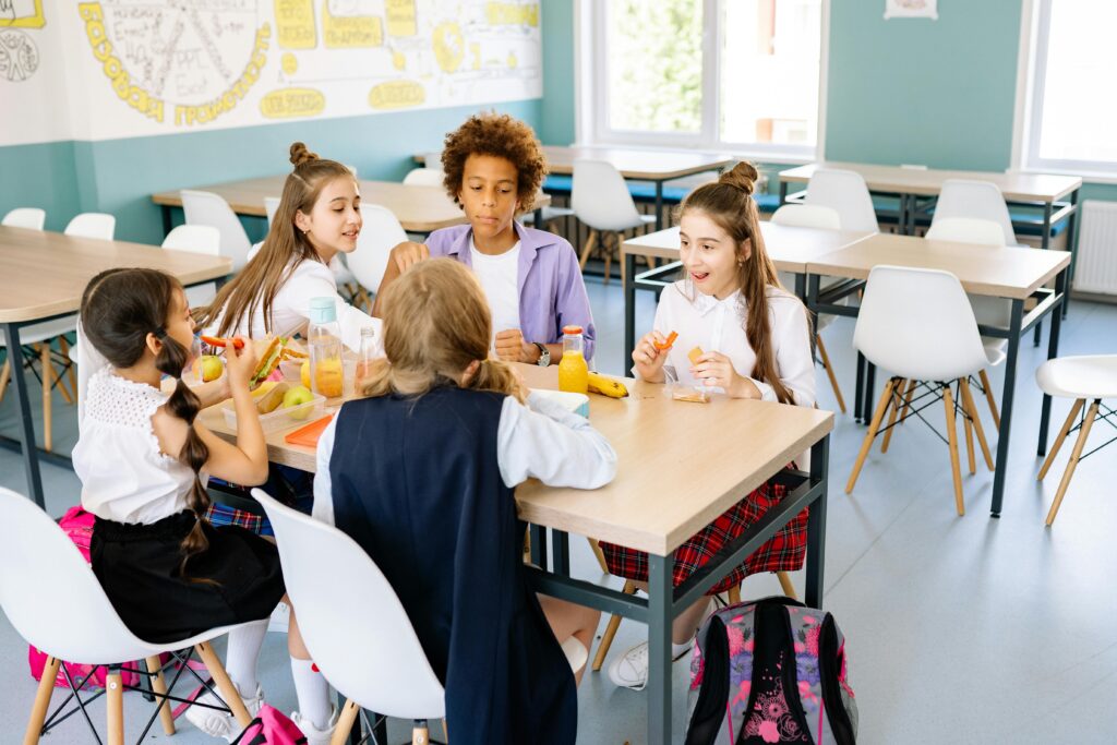 Students socializing during a gathering in a classroom, highlighting peer interaction and social development in school.