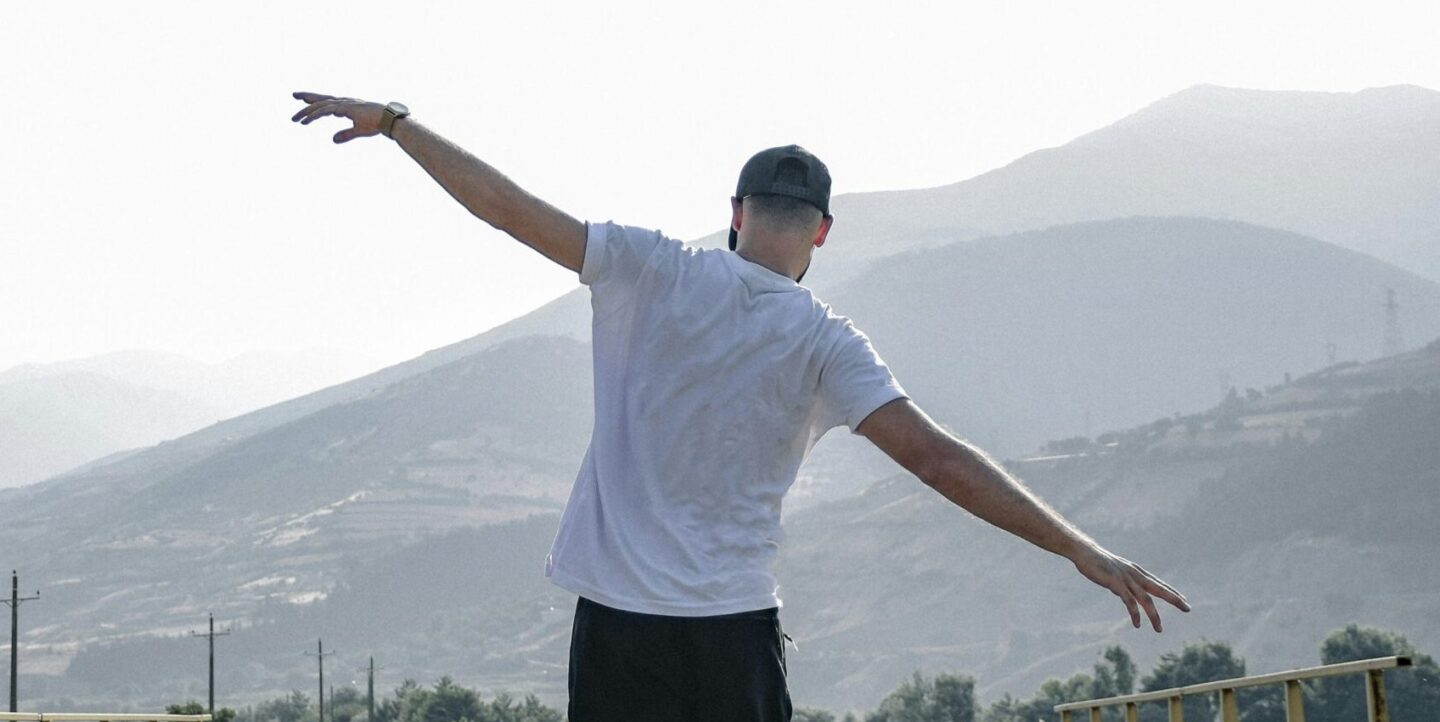 Person balancing on a railroad track with arms outstretched, representing balance between school, friendships, and self-care.