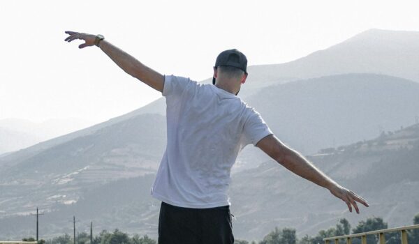 Person balancing on a railroad track with arms outstretched, representing balance between school, friendships, and self-care.