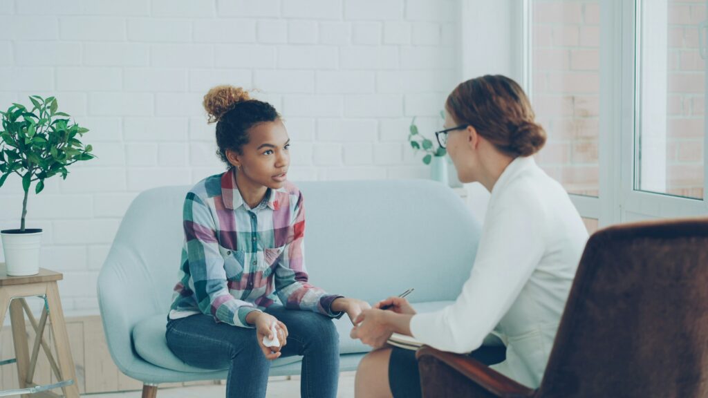 A teen engaging in a therapy session with a professional therapist, highlighting the importance of seeking support for mental health concerns.
