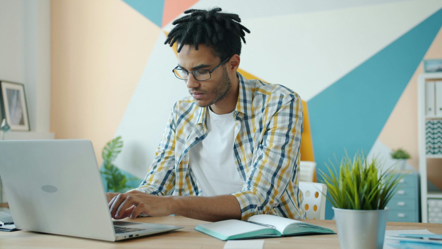 Teen studying at a desk using a laptop and notebook, illustrating focus and time management.