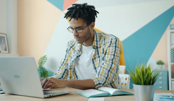 Teen studying at a desk using a laptop and notebook, illustrating focus and time management.