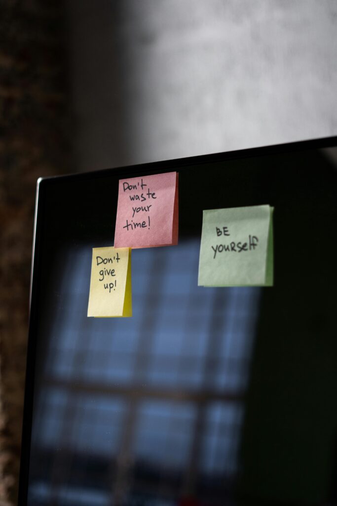 Colorful sticky notes with positive affirmations attached to a computer monitor, representing daily self-talk reminders for mental wellness.