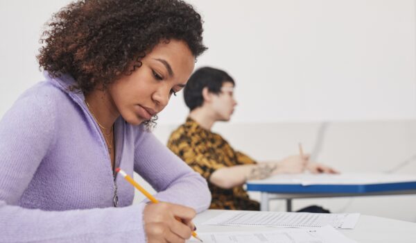 A teen in a purple sweater taking a test in a classroom.