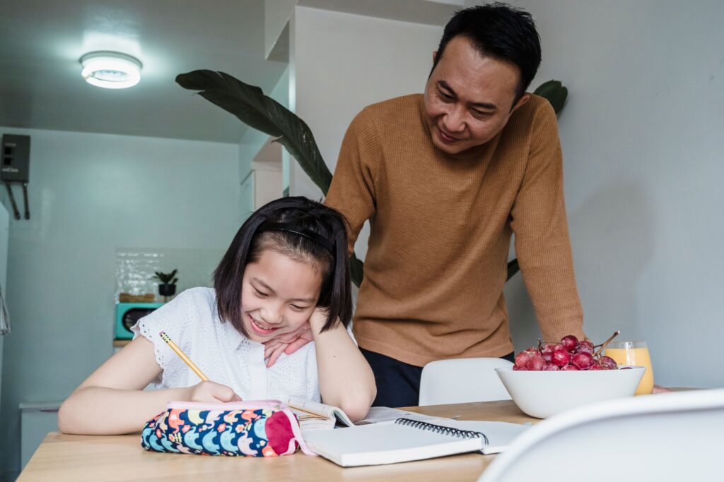A parent and teenager reviewing a weekly study schedule together at a kitchen table.