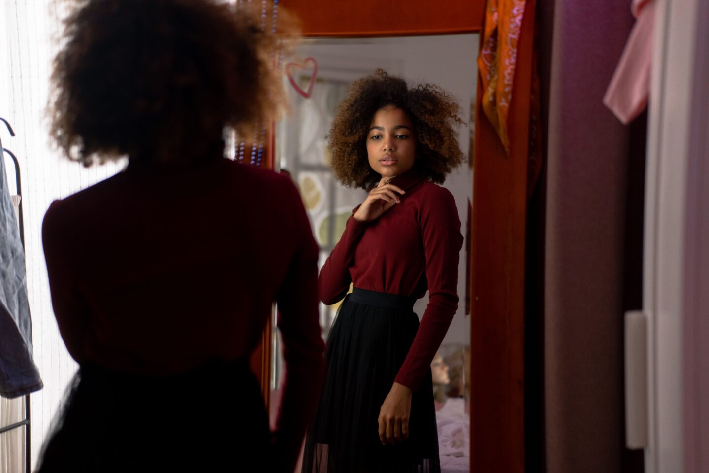 Teen girl looking at her reflection in a mirror, representing self-reflection and inner dialogue.