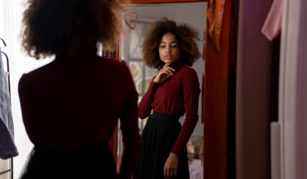 Teen girl looking at her reflection in a mirror, representing self-reflection and inner dialogue.