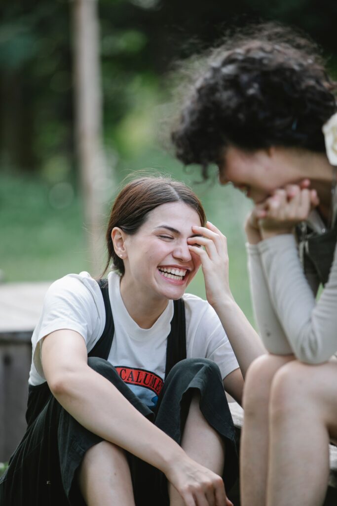Two teen girls laughing together outdoors, representing peer support and a positive self-image.