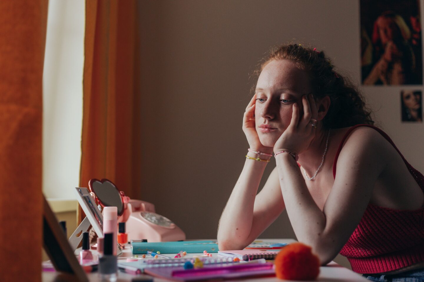 A teenager sitting at a desk, looking thoughtful, surrounded by schoolwork and an open journal.