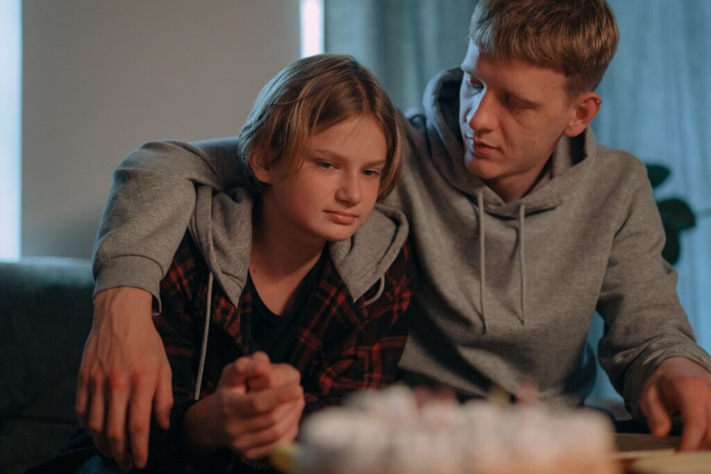 A supportive conversation between a teen and a caring adult in a warm, comfortable setting.
