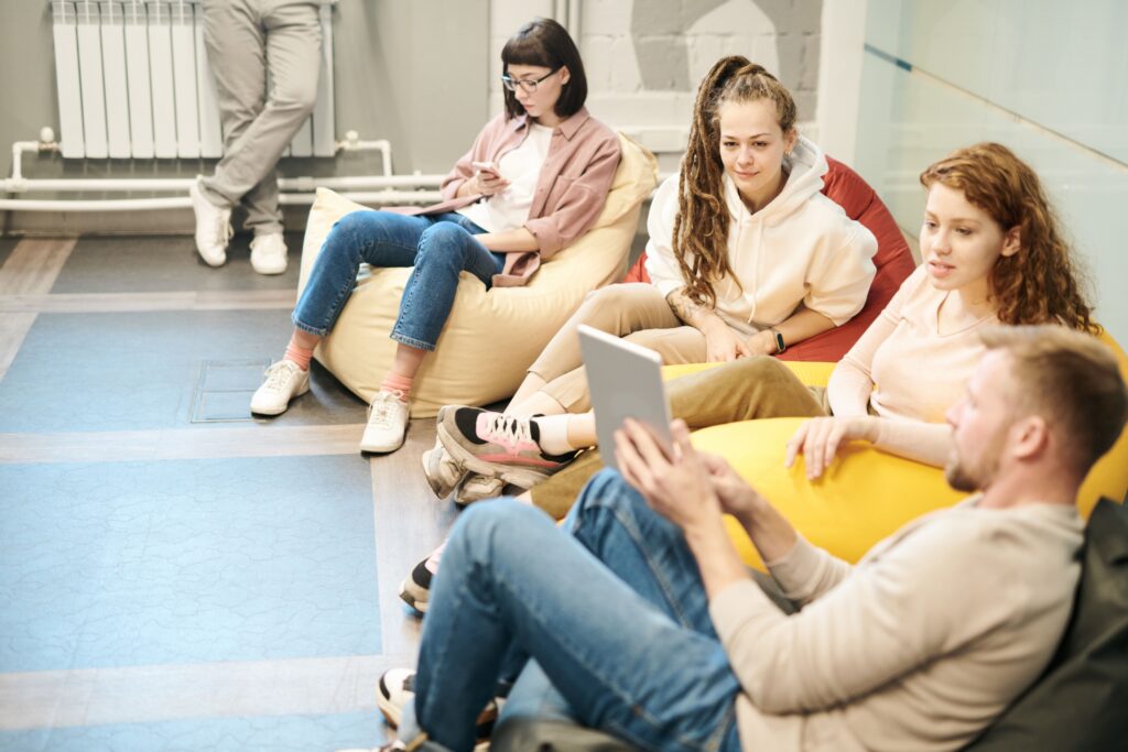 A group of teens sitting in a circle in a school or community setting, engaged in an open and supportive group conversation.