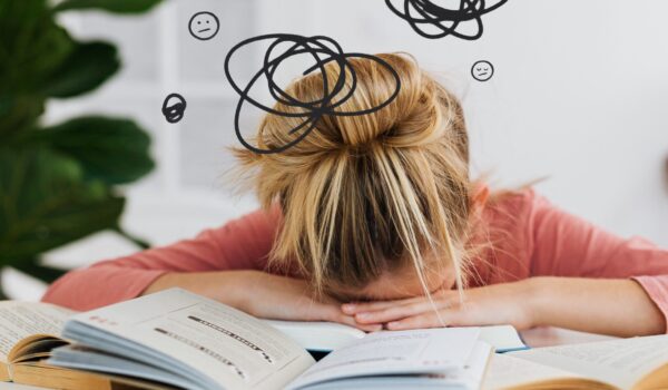 Student overwhelmed by schoolwork, head down on a stack of open books, with illustrated scribbles and worried expressions above representing racing thoughts and difficulty focusing.
