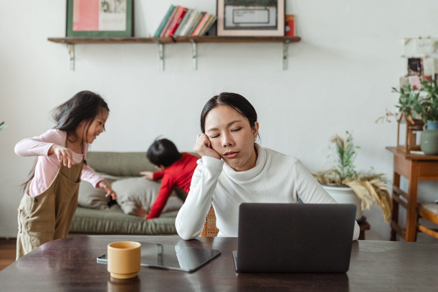 A tired parent sitting alone at a kitchen table with a cup of coffee, looking exhausted.
