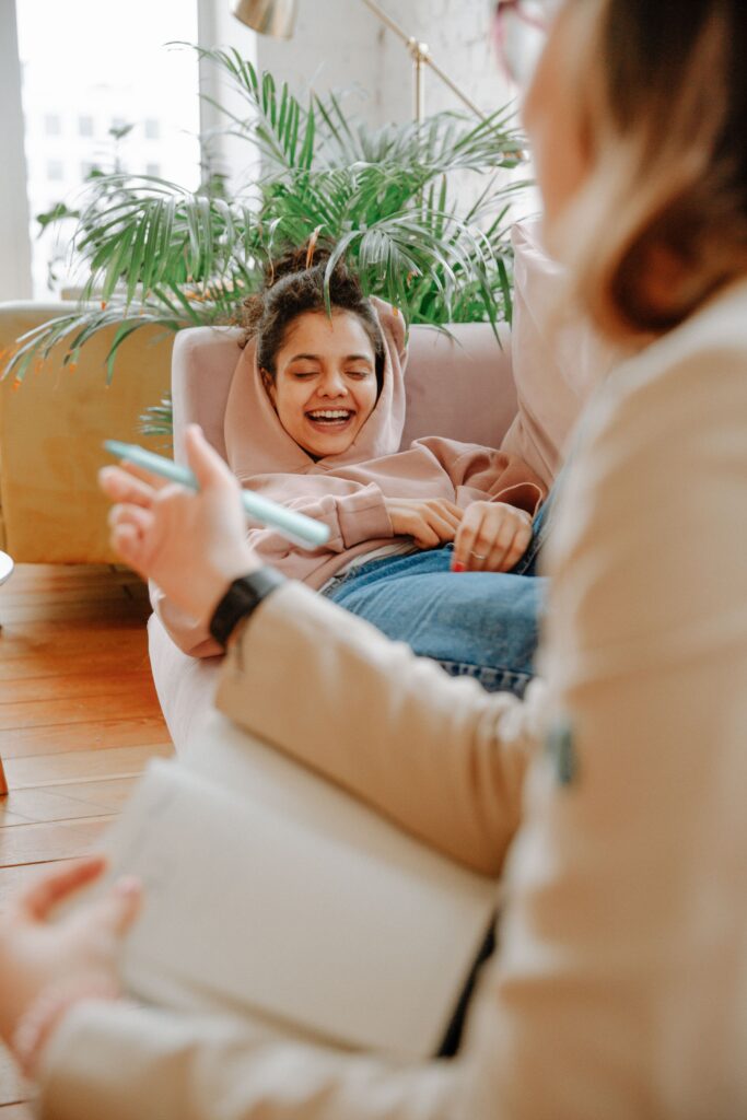 Therapy session on a cozy couch, while a teen is laughing and a therapist who is bringing comfort.